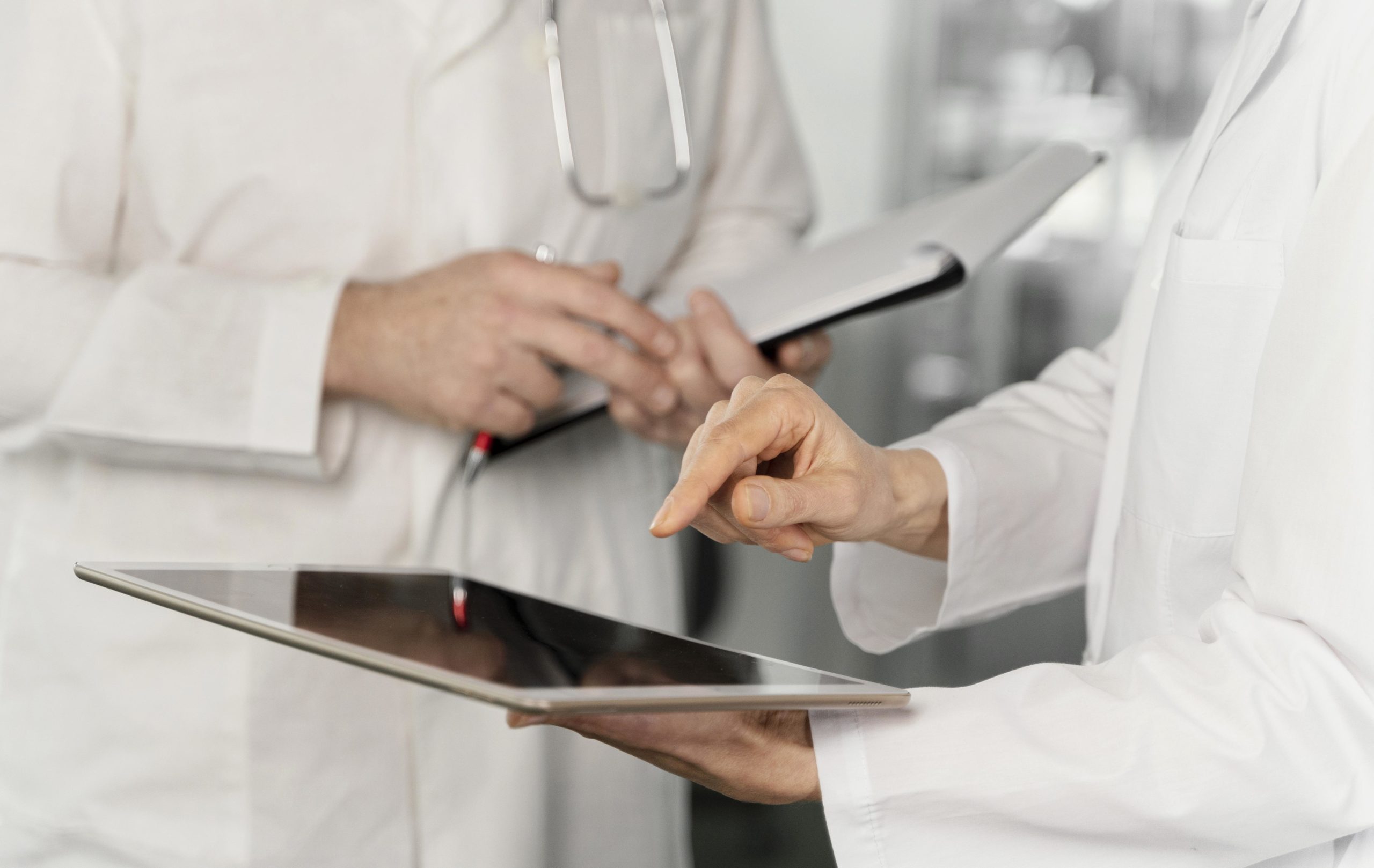 Mani di medici che consultano dati sanitari su un tablet.